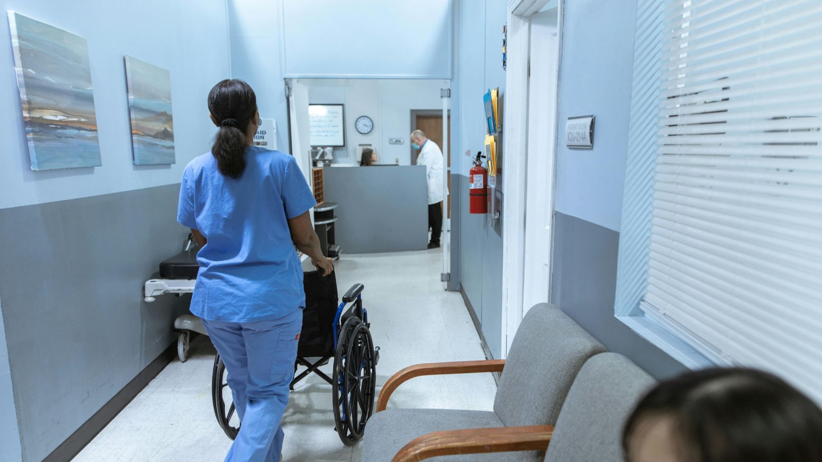Hospital porter transporting a patient in a wheelchair while glancing at a Trackerwave E-ink coaster